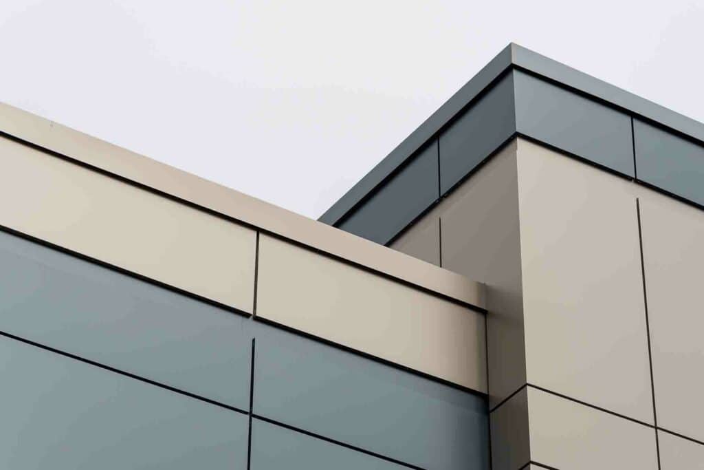 The exterior wall of a contemporary commercial style building with aluminum metal composite panels and glass windows. The fut